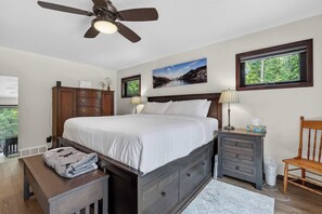 A bedroom with a bed, nightstands, a chair, a desk, a ceiling fan, and a window with a view. - Dog Friendly home in Baileys Harbor near Cana Island Lighthouse (Baileys Harbor)