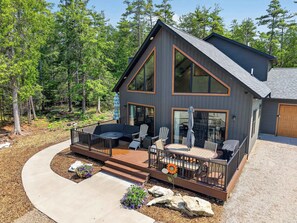 Une maison moderne à deux étages, dotée d’une terrasse, de grandes fenêtres et d’un garage.