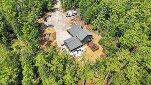 Une cabane de plain-pied dotée d’un patio couvert, entourée d’une forêt dense.