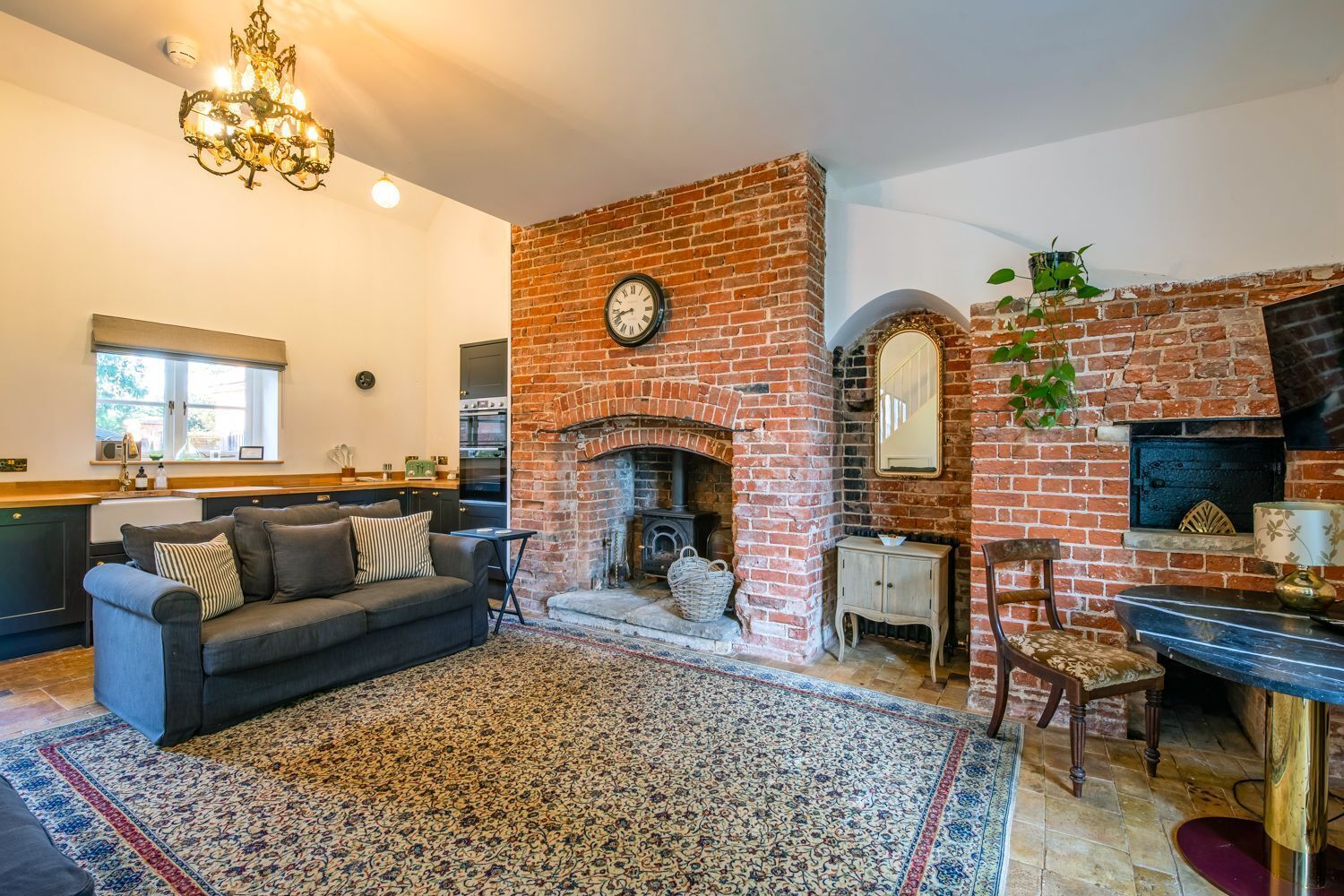 A living room with a fireplace, a sofa, a rug, and a dining area with a table and chairs.