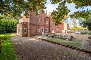 A brick building with a courtyard, picnic tables, and a barbecue area.