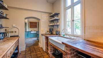 A kitchen with a large sink, wooden countertops, and a view through an archway to a dining area.