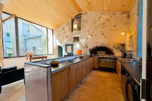 A modern kitchen with a stone wall, wooden ceiling, and a built-in oven. - Mounicat - Four Bedroom Villa, Sleeps 10 (Baleyssagues)
