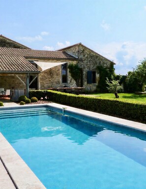 Une piscine avec une maison en pierre en arrière-plan.