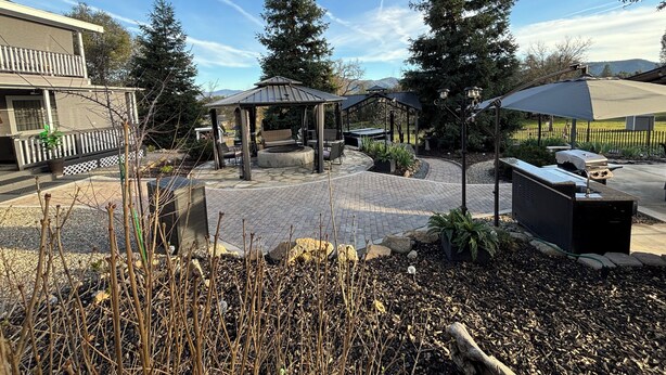 A patio area with a gazebo, outdoor seating, and a barbecue grill. - Two Sisters Inn (Ahwahnee)