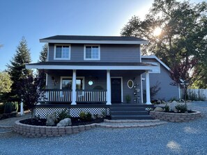 A two-story house with a front porch, a garage, and a well-maintained garden. - Two Sisters Inn (Ahwahnee)