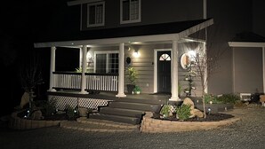 A two-story house with a porch, steps, and a garden. - Two Sisters Inn (Ahwahnee)