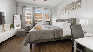 Moderni hotellihuone, jossa on suuri sänky, työpöytä ja kattotuuletin.