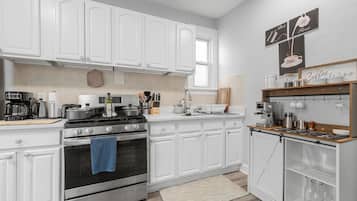 A modern kitchen with white cabinetry, a built-in oven, a coffee station, and a coffee machine.