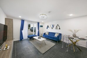 A modern living room with a sofa, a coffee table, and a TV. - Chapel Street Suite - Grampian Lettings (Aberdeen)