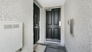Ein schmaler Flur mit einer schwarzen Tür und einem weißen Heizkörper links.