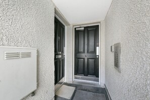 A narrow hallway with a black door and a white radiator on the left. - Chapel Street Suite - Grampian Lettings (Aberdeen)