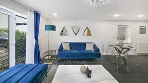 Ein modernes Wohnzimmer mit einem blauen Sofa, einem Couchtisch und einer Kronleuchter.