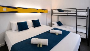 Une chambre d’hôtel avec un lit superposé, un lit simple et un mur décoratif.