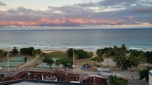 Vista costera con playa, palmeras y una cancha deportiva.