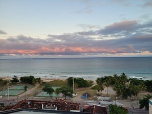 Blick auf die Küste mit Strand, Palmen und einem Sportplatz.