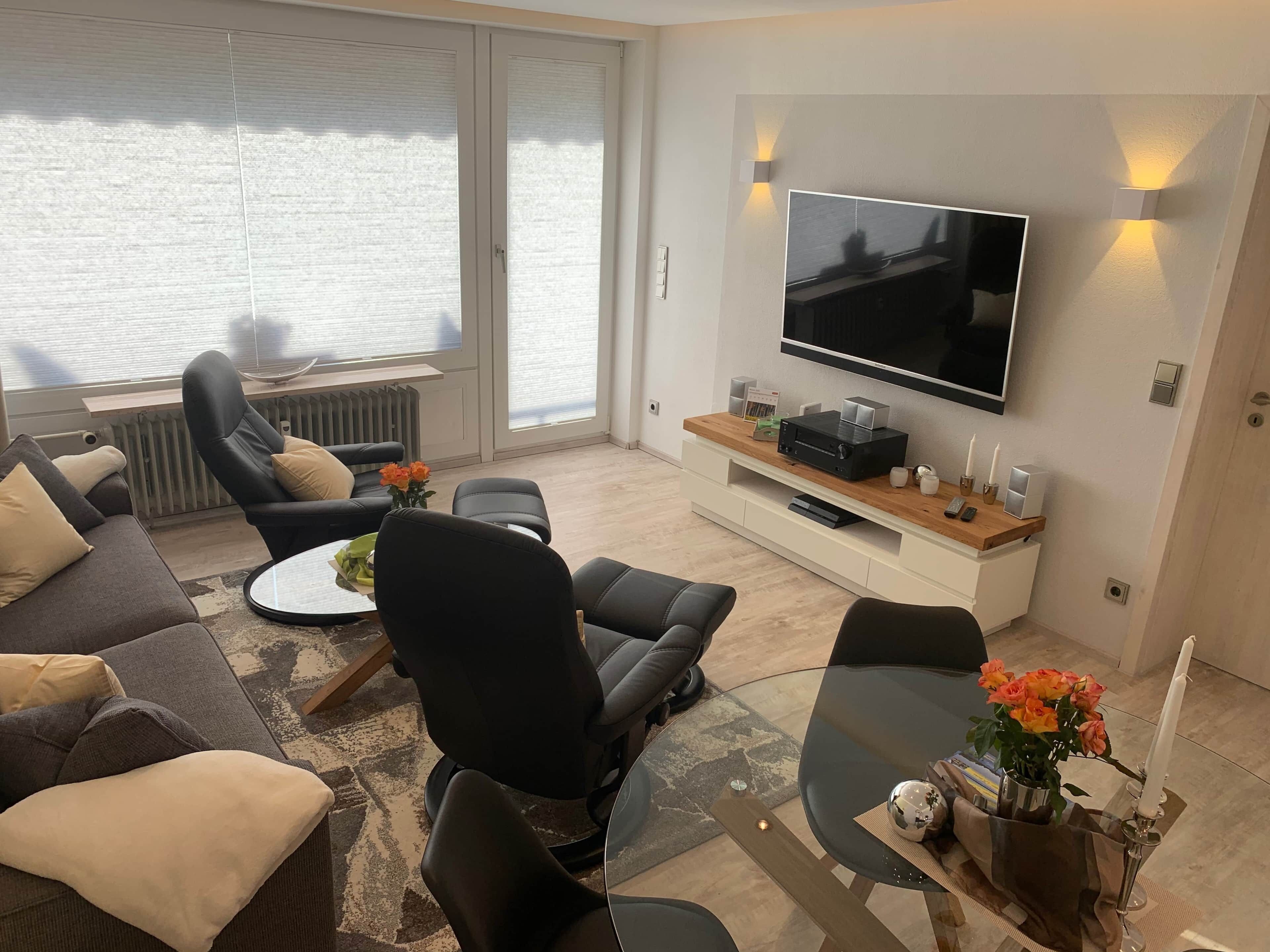 Una sala de estar moderna con un sofá, sillas, una mesa de centro, un televisor y una chimenea.