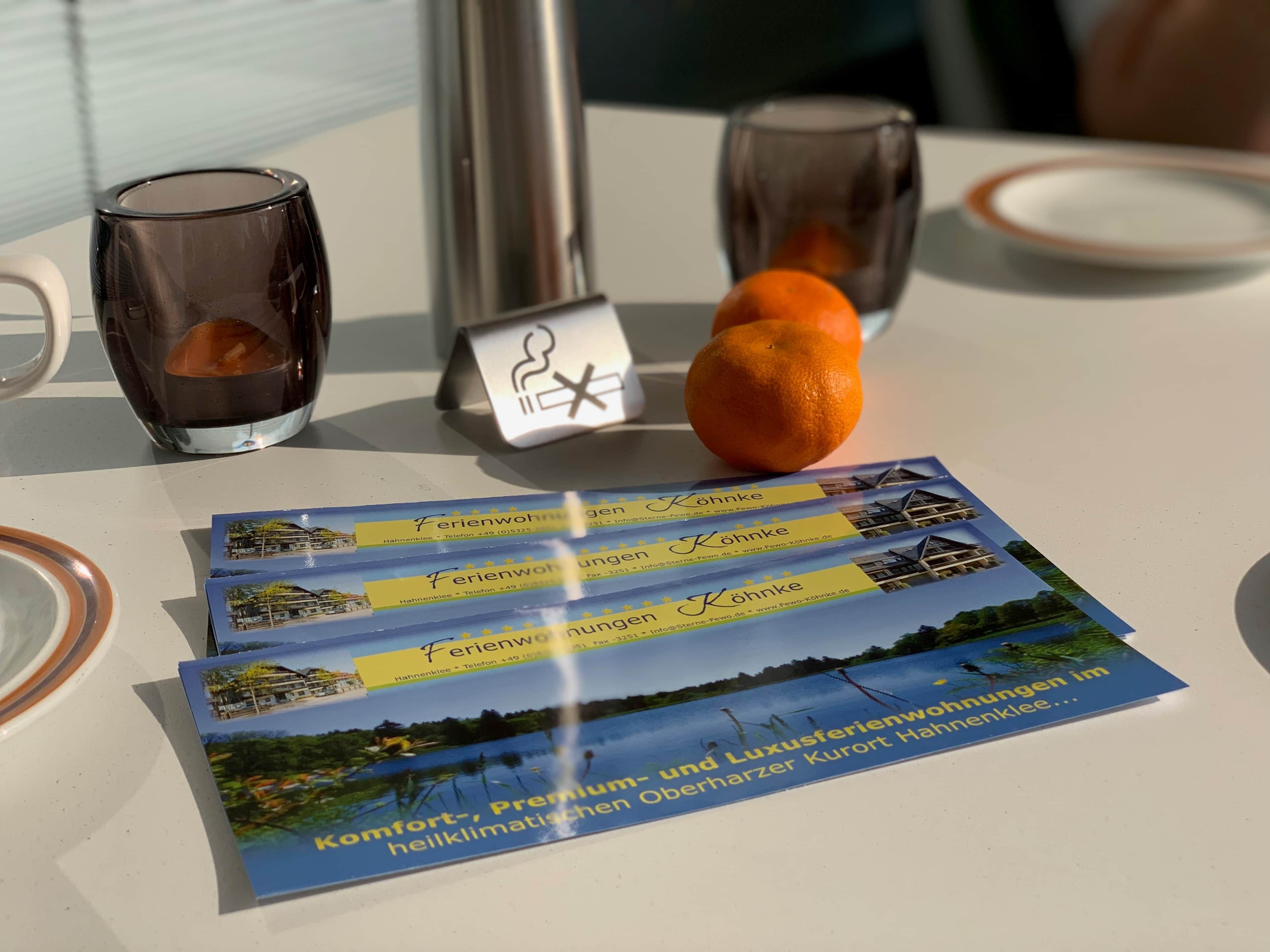 A table with a glass of water, a glass of juice, a plate, and brochures for a hotel.