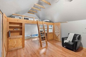 A loft bedroom with a wooden ladder, a black leather chair, and a view of the sky. - Historic Old Town Attic Loft—Steps from Albuquerque’s Best Sights (Albuquerque)