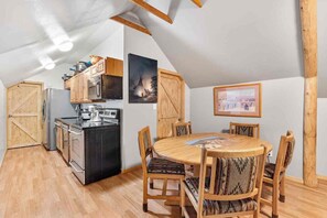 A compact kitchen with modern appliances, a dining table with chairs, and wooden beams on the ceiling. - Historic Old Town Attic Loft—Steps from Albuquerque’s Best Sights (Albuquerque)