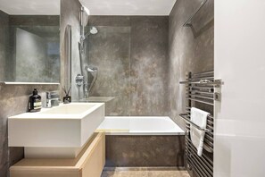 Ein modernes Badezimmer mit einem großen, weißen Waschbecken, einer Badewanne und einer Duschkabine.