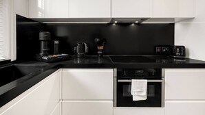 Eine moderne Küche mit schwarzem Arbeitsplatz, weißen Schränken, einer Kaffeemaschine, einem Wasserkocher und einem Toaster.