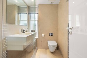 Une salle de bain moderne avec une douche à parois de verre, un lavabo blanc et des toilettes.