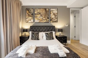 Ein Hotelzimmer mit einem großen Bett, zwei Nachttischen, einem Kopfteil und abstrakter Kunst an der Wand.