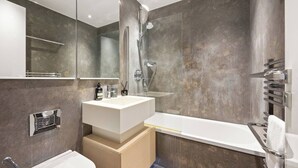 Ein modernes Badezimmer mit großem Spiegel, weißem Waschbecken, einer Badewanne und einer Duschkabine.