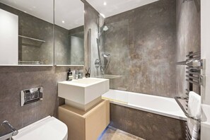 Ein modernes Badezimmer mit großem Spiegel, weißem Waschbecken, einer Badewanne und einer Duschkabine.