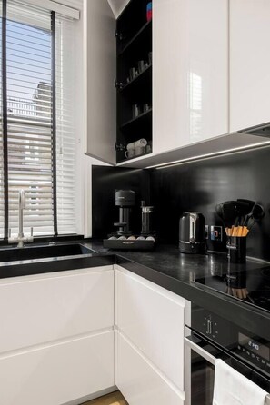 A modern kitchen with white cabinetry, a black countertop, and a built-in oven. - The Duke Residence / 3Bed 2.5Bath in Mayfair (Greater London)