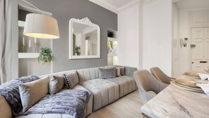 Ein modernes Wohnzimmer mit einer Couch, einem Esstisch und einem Spiegel.