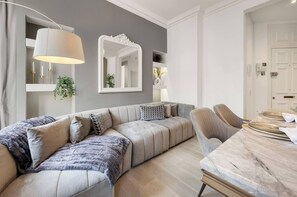 Ein modernes Wohnzimmer mit einer Couch, einem Esstisch und einem Spiegel.