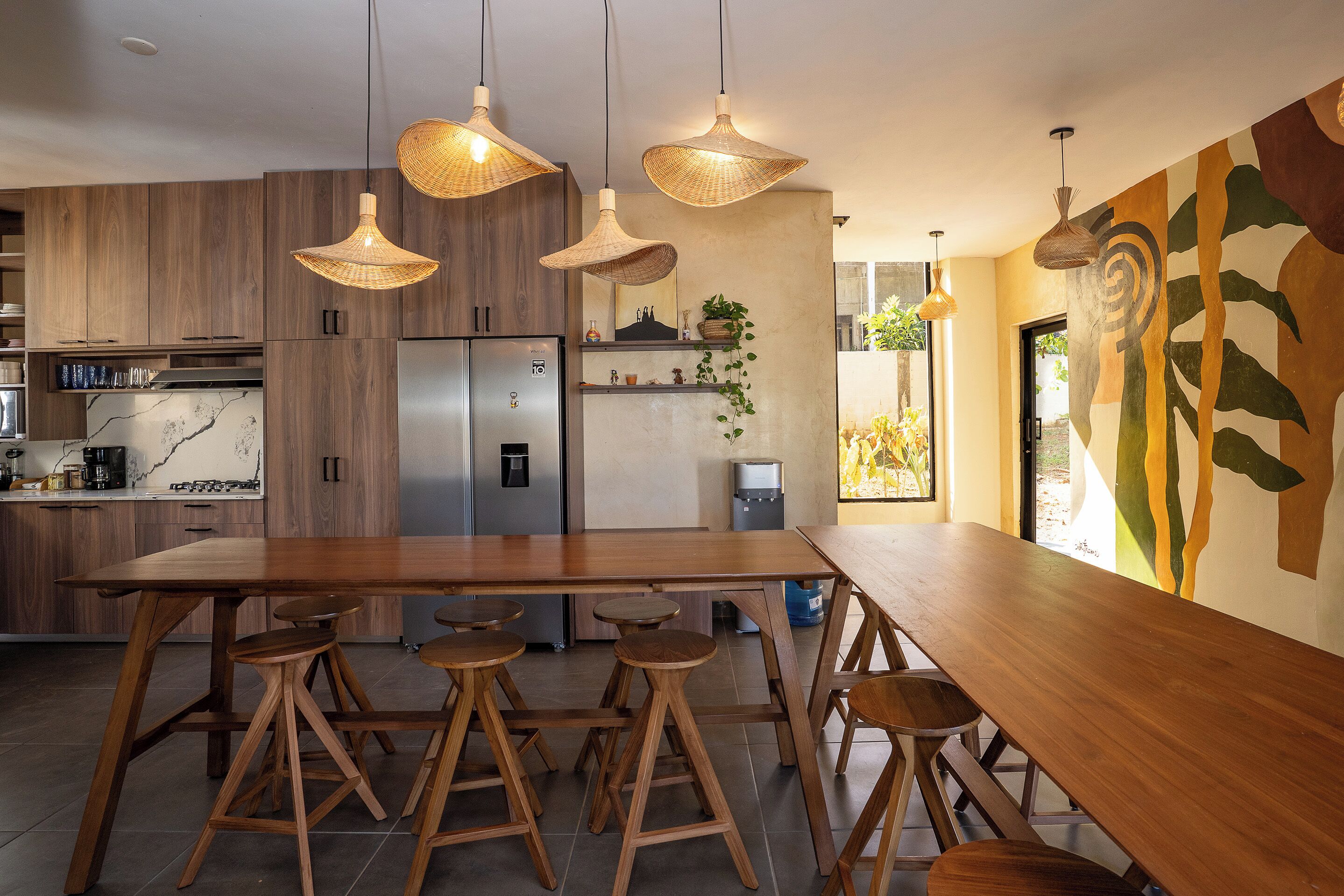 Eine moderne Küche mit Holzschränken, einem Edelstahlkühlschrank und einem großen Esstisch mit Hockern.