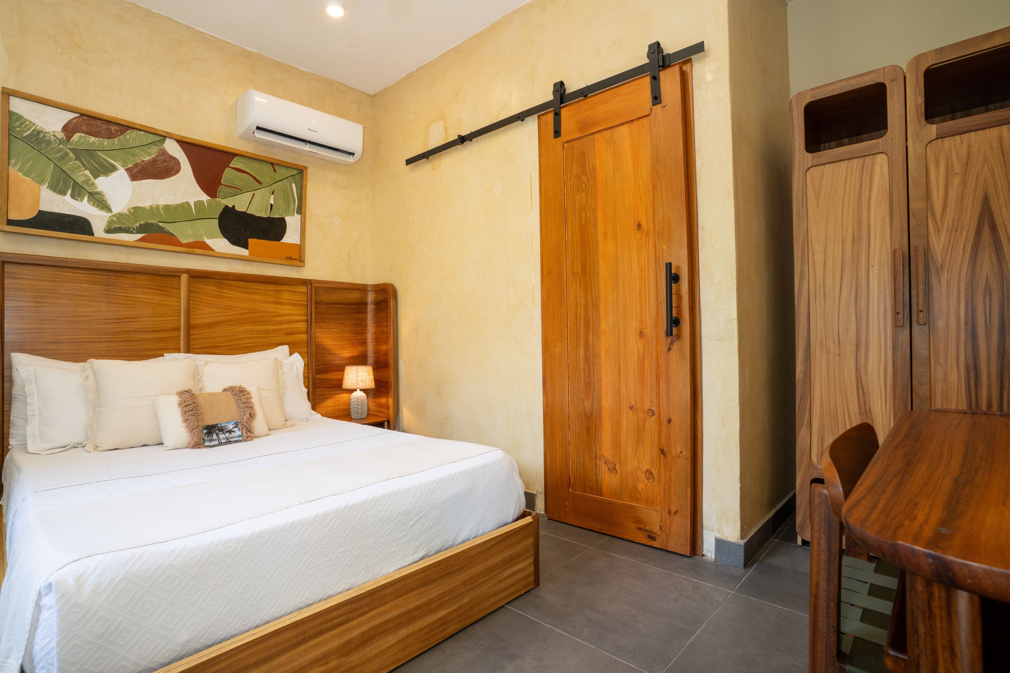 A bedroom with a bed, bedside table, lamp, and a wooden wardrobe.