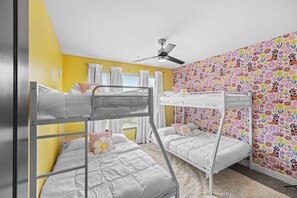 A bunk bed room with a ceiling fan, white bedding, and a floral wallpaper. - Vibrant Nashville Retreat, Pool and Glam Room (Nashville)