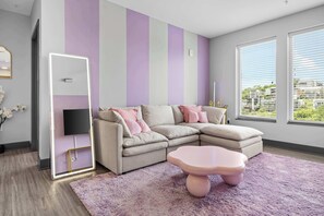 A modern living room with a sectional sofa, a flat-screen TV, and a pink accent table. - Vibrant Nashville Retreat, Pool and Glam Room (Nashville)