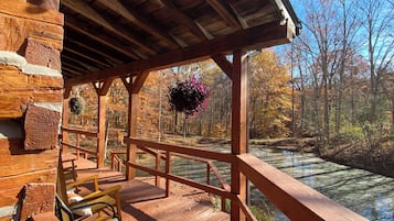 Une terrasse en bois, dotée de bancs, qui offre une vue sur une zone boisée et un plan d’eau.