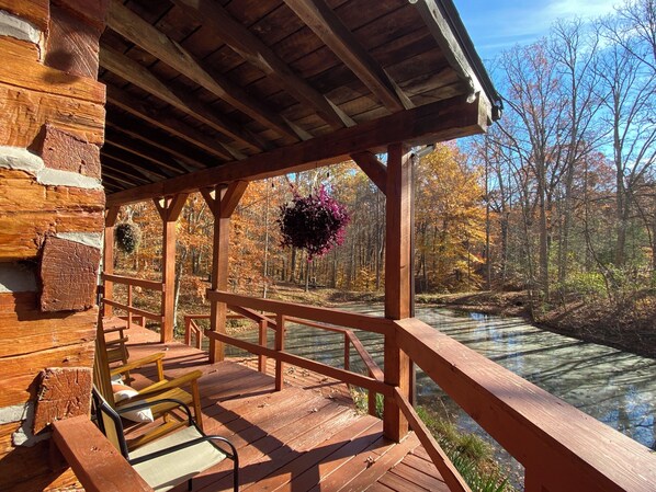 Une terrasse en bois, dotée de bancs, qui offre une vue sur une zone boisée et un plan d’eau.