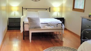 Une chambre à coucher avec un lit, des lampes de chevet, un ventilateur de plafond, une horloge murale et une fenêtre avec un rideau.