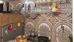 Una cuina amb rajoles estampades, un rentaplatets d'acer inoxidable i un escorredís.