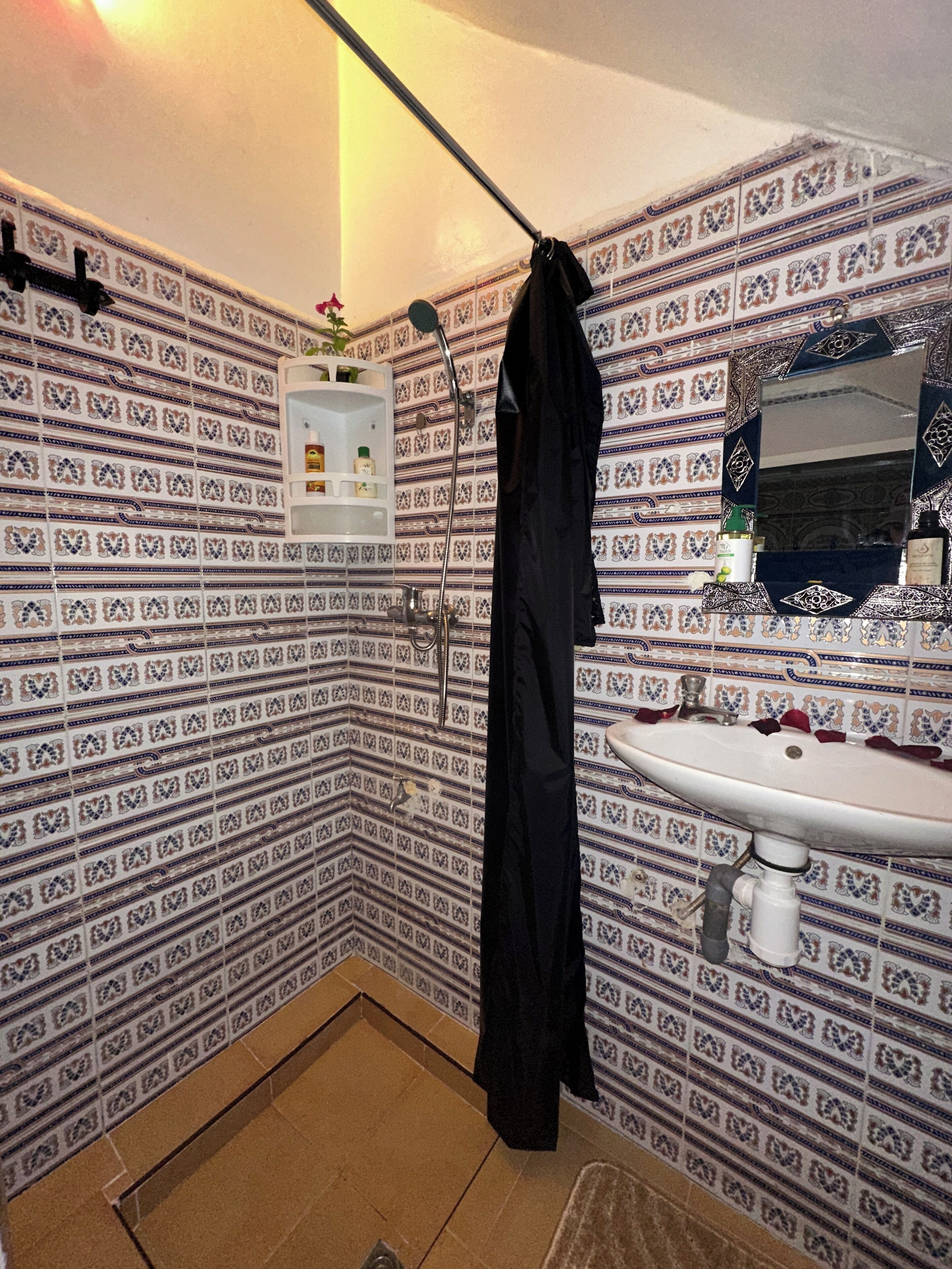 Een badkamer met patroon tegels, een wastafel, een spiegel en een douchehoek.