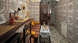 Una habitació amb mosaics decoratius, un sofà tradicional, una taula petita amb objectes ornamentals i una làmpada penjant.