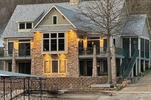 Una casa de varios pisos con fachada de piedra, amplias ventanas y una escalera que conduce al nivel superior.