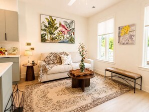 A living room with a sofa, coffee table, and a view of the outdoors. - The Jardin Rose Suite | Near Downtown (Savannah)