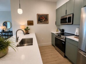 Eine moderne Küche mit Edelstahlgeräten, einer weißen Arbeitsplatte und Holzboden.