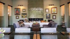 A modern hotel lobby with two sofas, a coffee table, framed artwork, and a large metallic sign. - The Jardin Violet Suite Near Downtown (Savannah)