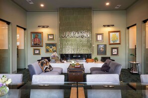 Eine moderne Hotellobby mit zwei Sofas, einem Couchtisch, gerahmten Kunstwerken und einem großen Metallschild.