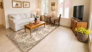 Una sala de estar con sofá, mesa de centro, televisor y un comedor con sillas y mesa.