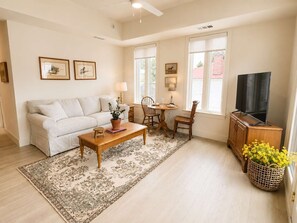Ein Wohnzimmer mit einer Couch, einem Couchtisch, einem Fernseher und einem Essbereich mit Stühlen und einem Tisch.